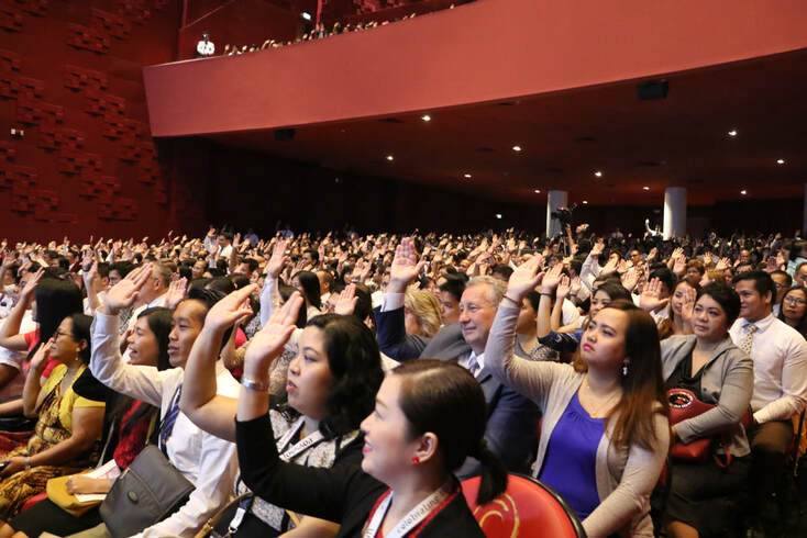 Hundreds of Latter-day Saints in the Philippines raising their right hands to sustain someone as the 100th stake in the country is created.